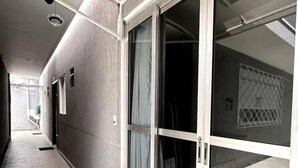 Un corridoio con una porta scorrevole in vetro che dà su una stanza con pavimento piastrellato e ringhiera in metallo.