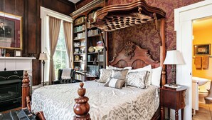 A large bed with a wooden headboard, a bookshelf, a fireplace, and a bathroom visible through an open door. - 7 Private Rooms, Country Setting Bourbon Trail, patio/firepit. Breakfast inc. (Springfield)