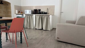 Un espace de vie compact comprenant un coin cuisine, un coin repas avec une table et des chaises, et un canapé.