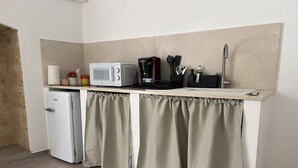 Une petite cuisine équipée d’un réfrigérateur, d’un four à micro-ondes, d’une machine à café et d’un évier.