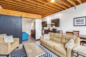 A modern living room with a sofa, coffee table, and a dining area with chairs and a table. - Roxy Condo 203 in Bremerton (Bremerton)