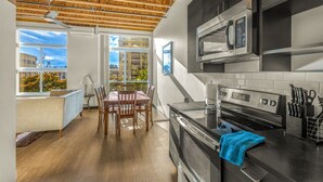 A modern kitchen with a wooden ceiling, built-in appliances, and a dining area with a view. - Tracyton Condo 202 in Bremerton (Bremerton)