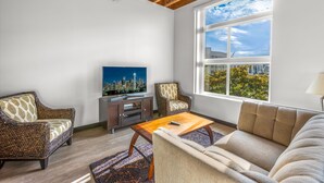 A living room with a cityscape TV, a sofa, a chair, and a wooden ceiling. - Tracyton Condo 202 in Bremerton (Bremerton)