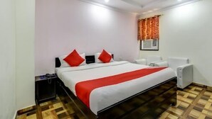 Une chambre d’hôtel avec un grand lit, une table de chevet, une chaise et une fenêtre avec des rideaux.