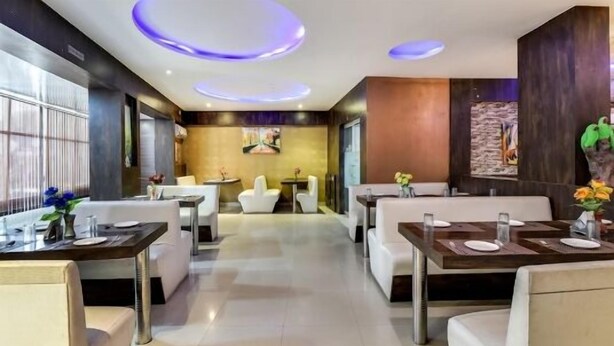 Un restaurant moderne avec des meubles blancs, un espace de restauration central et un mur d’accent en pierre.