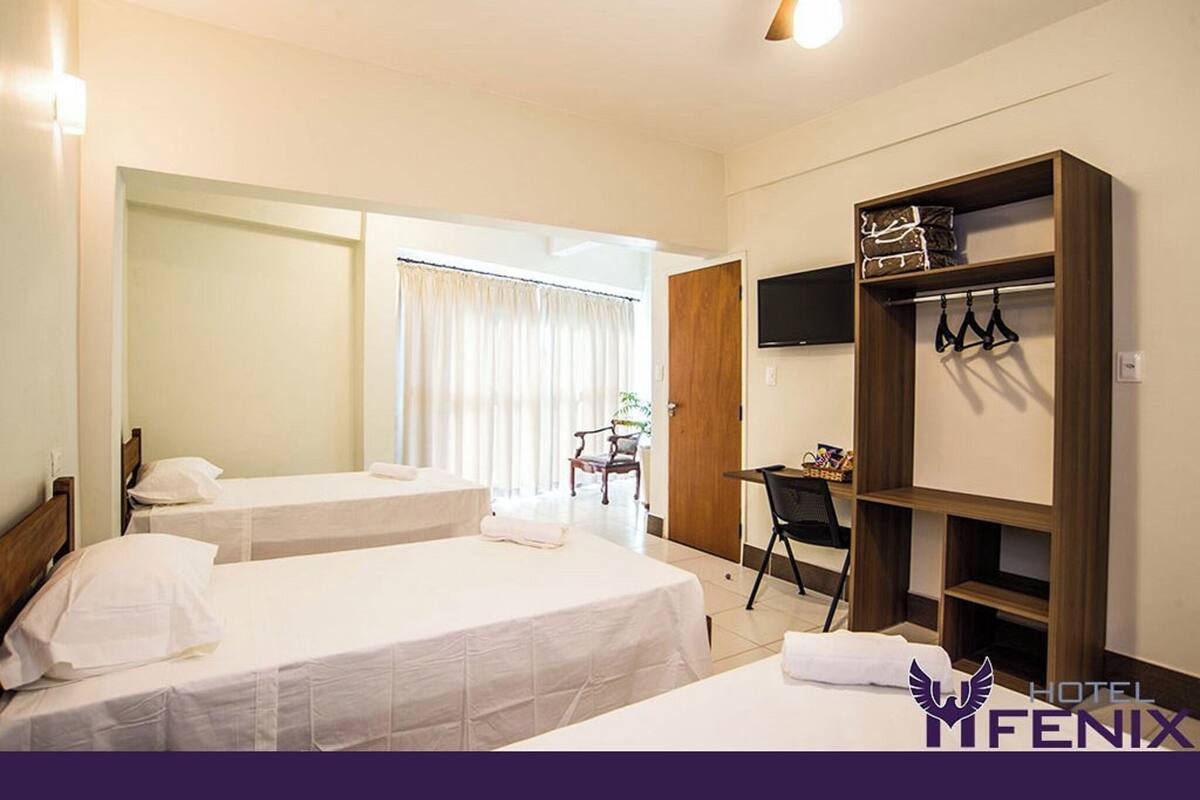 A hotel room with two beds, a desk, a chair, a TV, and a wardrobe.