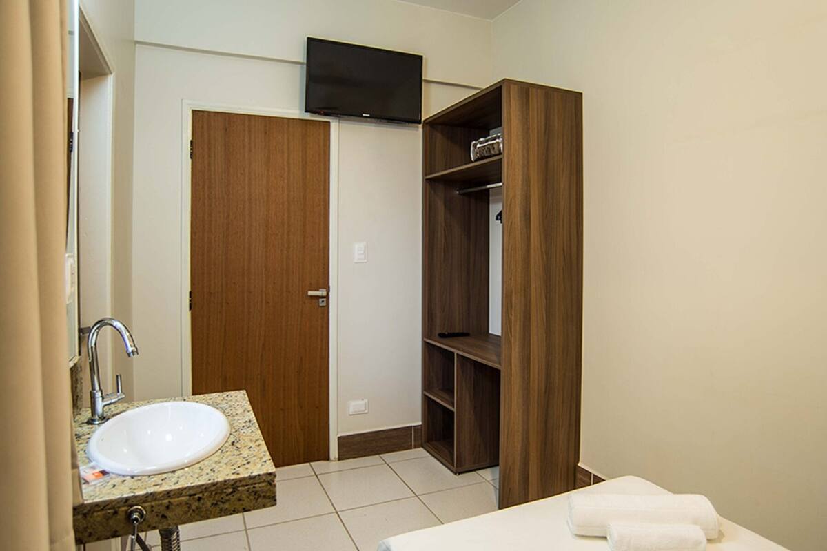 A bathroom with a sink, mirror, and wooden shelving unit.
