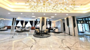 A spacious lobby with a marble floor, modern furniture, and a unique ceiling design. - Seven Seas Hotel  (Dubai)