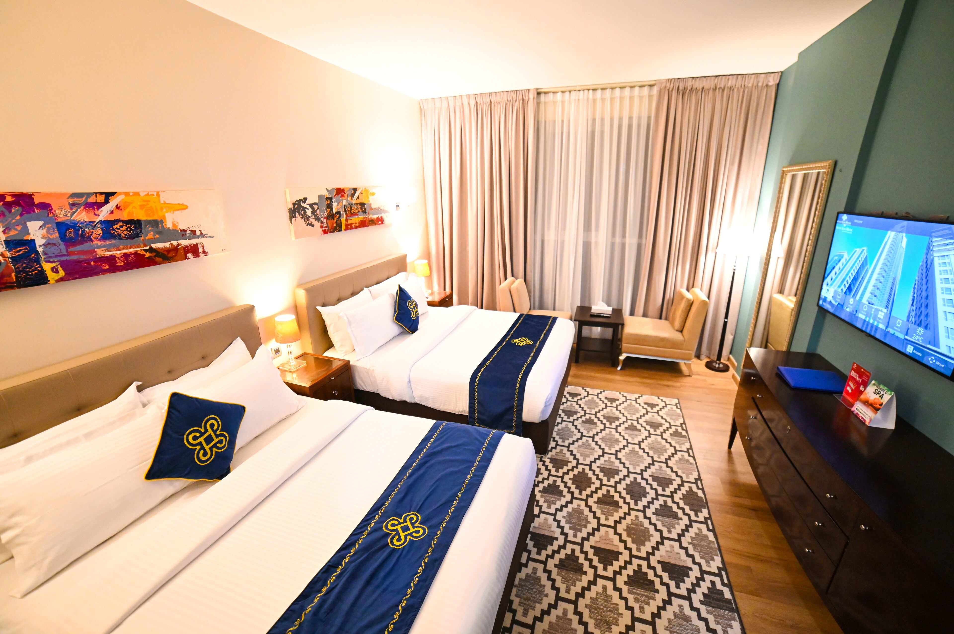 Une chambre d’hôtel avec deux lits, une télévision, un bureau et un tapis à motifs.