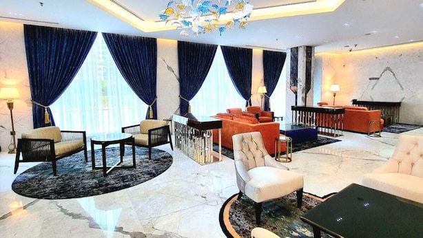 A spacious lobby with a marble floor, a central seating area with sofas and armchairs, a decorative chandelier, and large windows with blue curtains. - Seven Seas Hotel  (Dubai)