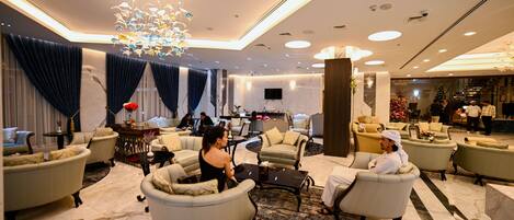 A spacious lobby with multiple seating areas, a large chandelier, and a modern ceiling design.