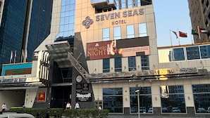 A tall hotel with a modern glass facade, a prominent logo, and a sign for 'Arabic Afro Night' below the entrance. - Seven Seas Hotel  (Dubai)