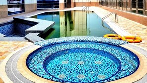 A rooftop pool with a mosaic design, surrounded by a building with large windows and a tiled floor. - Seven Seas Hotel  (Dubai)