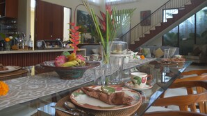 A dining area with a glass table, chairs, and a variety of dishes and drinks.