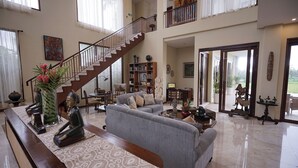 A spacious living room with a staircase, a sofa, a coffee table, and a bookshelf.