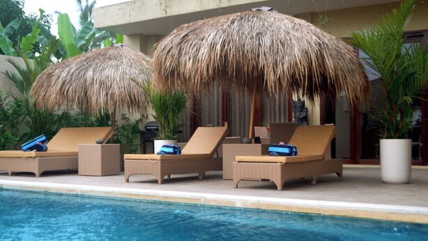 A poolside area with lounge chairs and thatched umbrellas.