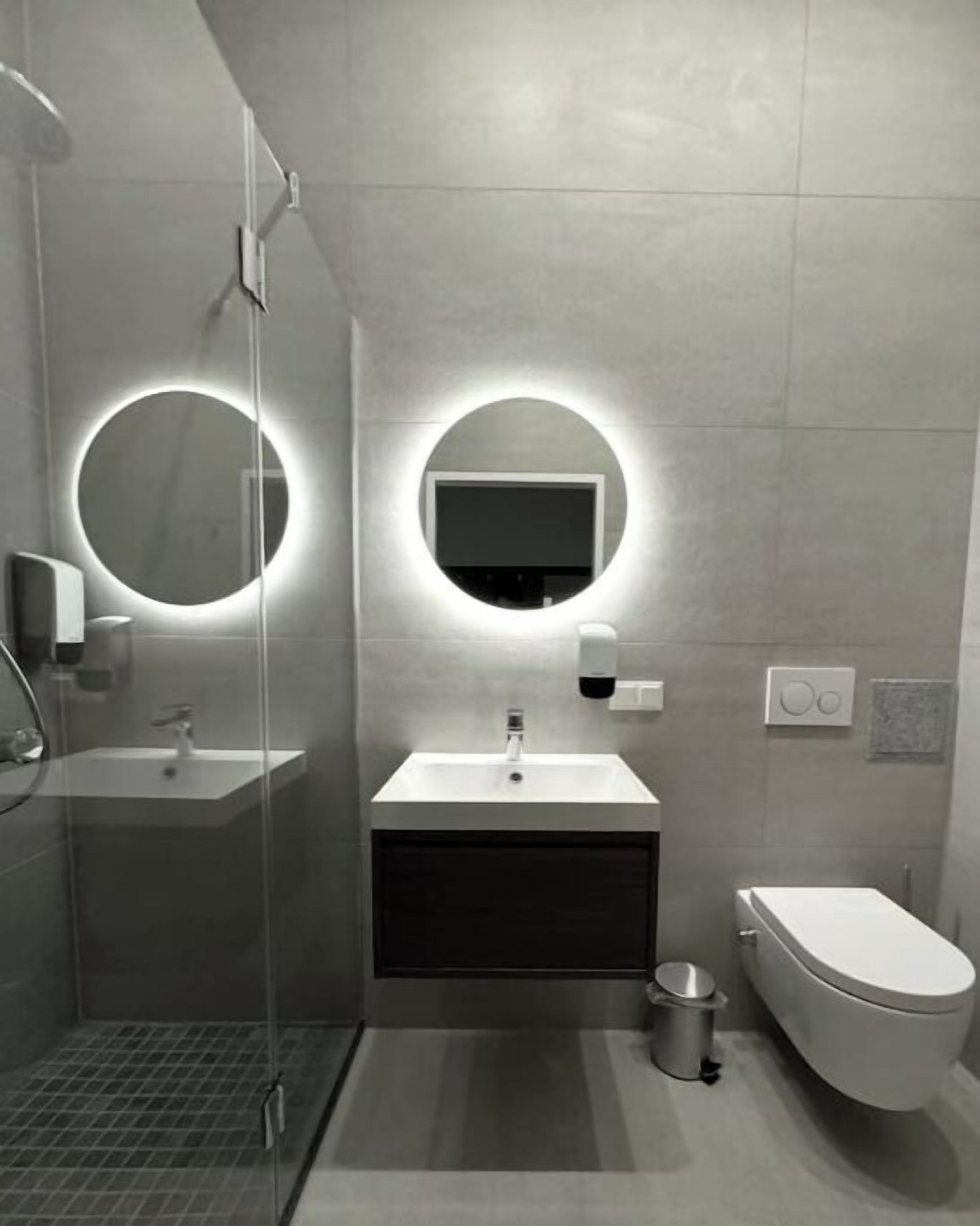 A modern bathroom with a glass shower enclosure, a sink with a mirror, and a toilet.