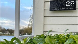 A house number sign for 'Lake's End Lodge' with a view of a lake and a white building. - Lake’s End Lodge.  (South Cerney)