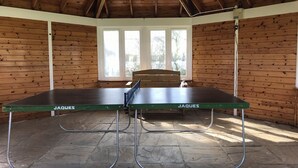 A ping pong table with "JAQUES" branding in a room with wooden walls and a sloped ceiling. - Lake’s End Lodge.  (South Cerney)