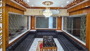 Een moderne woonkamer met een zwart hoekbank, een glazen scheidingswand en een kroonluchter.