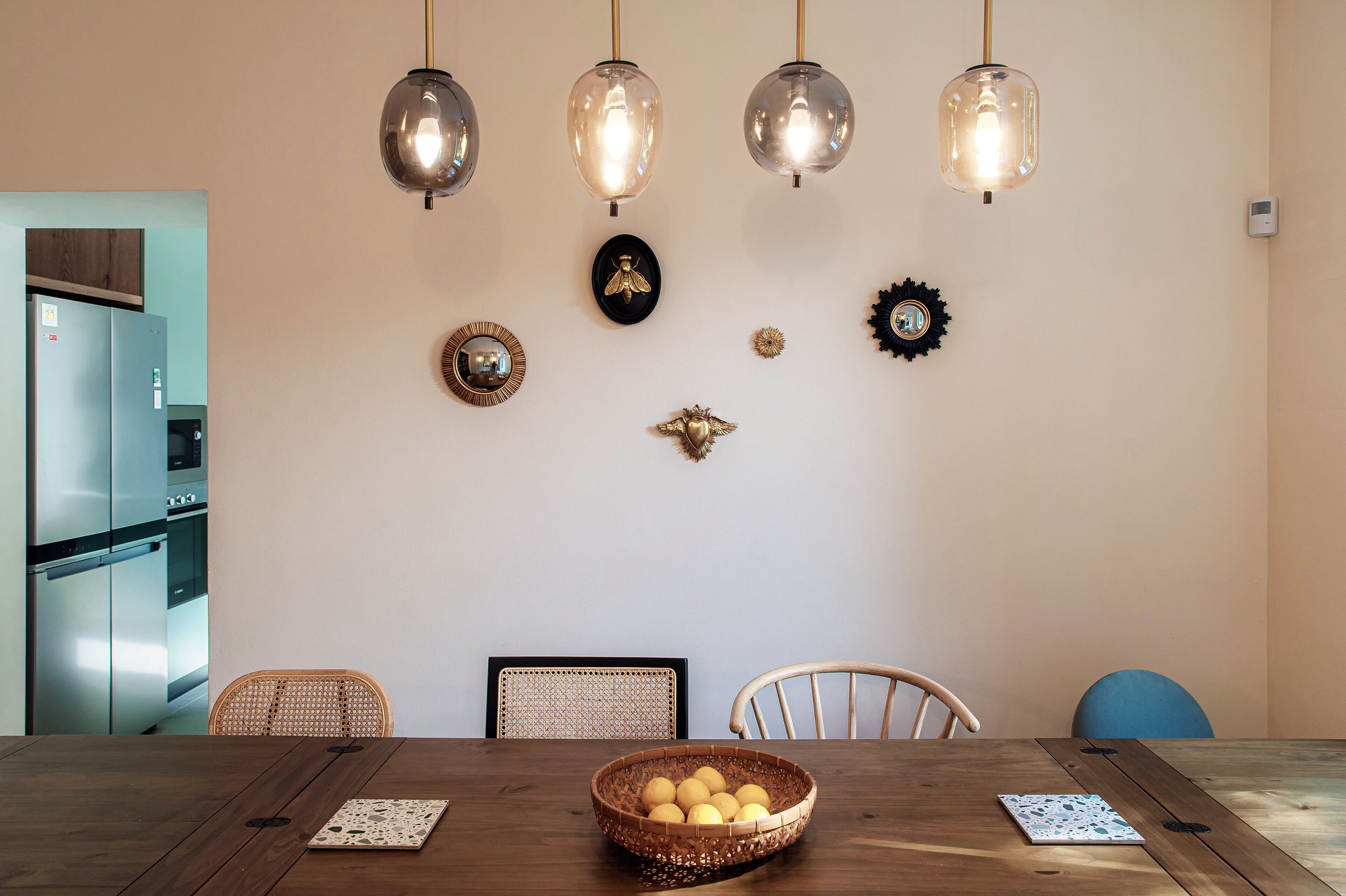 A dining area with a wooden table, wicker chairs, and a basket of lemons.