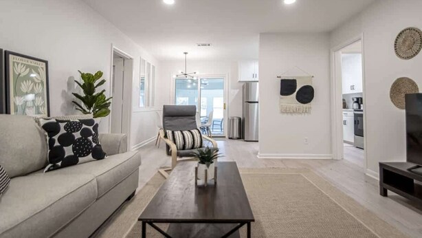 Uma sala de estar moderna com sofá, mesa de centro e um espaço de jantar com cadeiras.