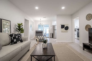 A modern living room with a sofa, coffee table, and a dining area with chairs.