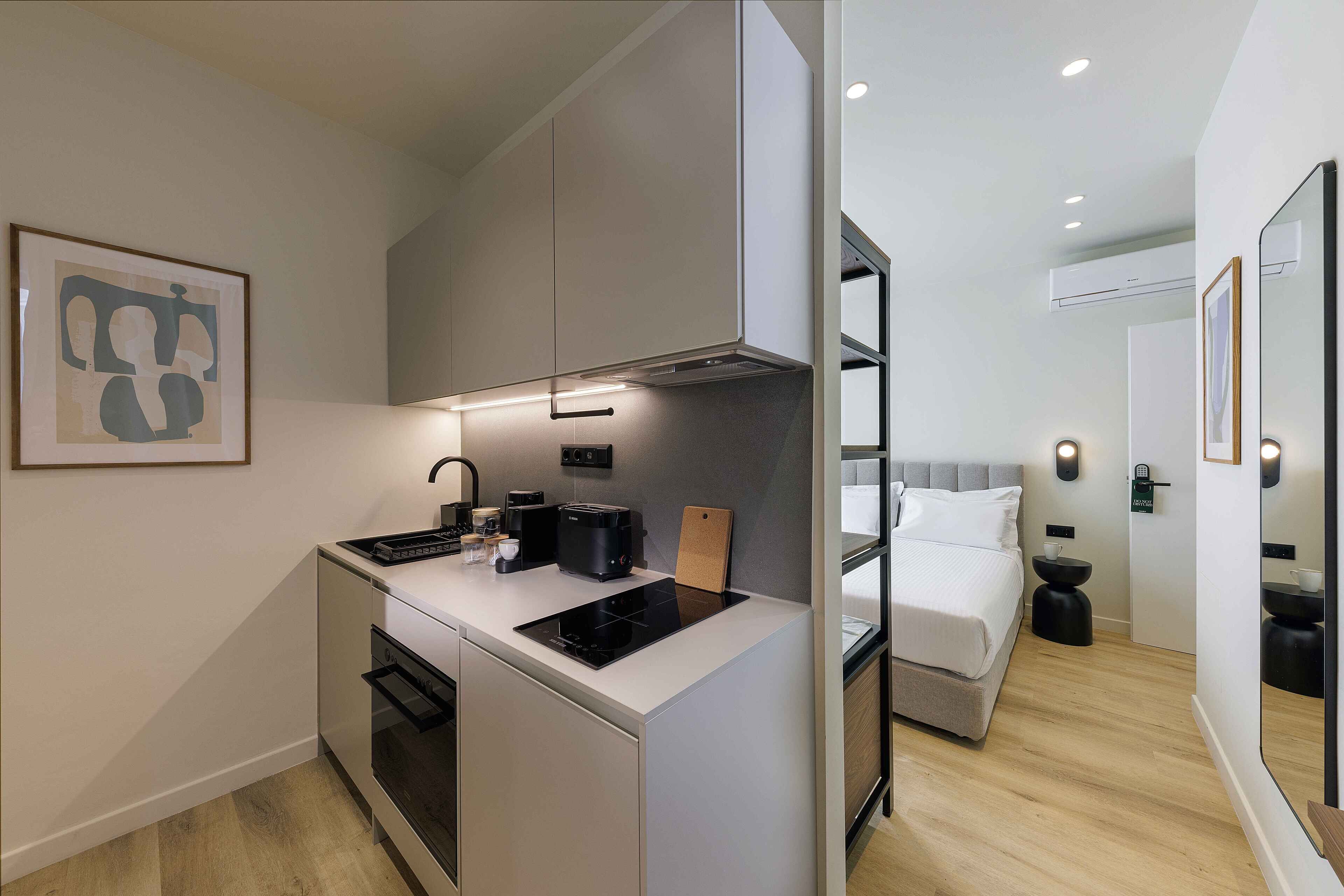 Une cuisine compacte dotée d’appareils électroménagers modernes, un coin repas et une chambre avec un lit et une table de chevet.