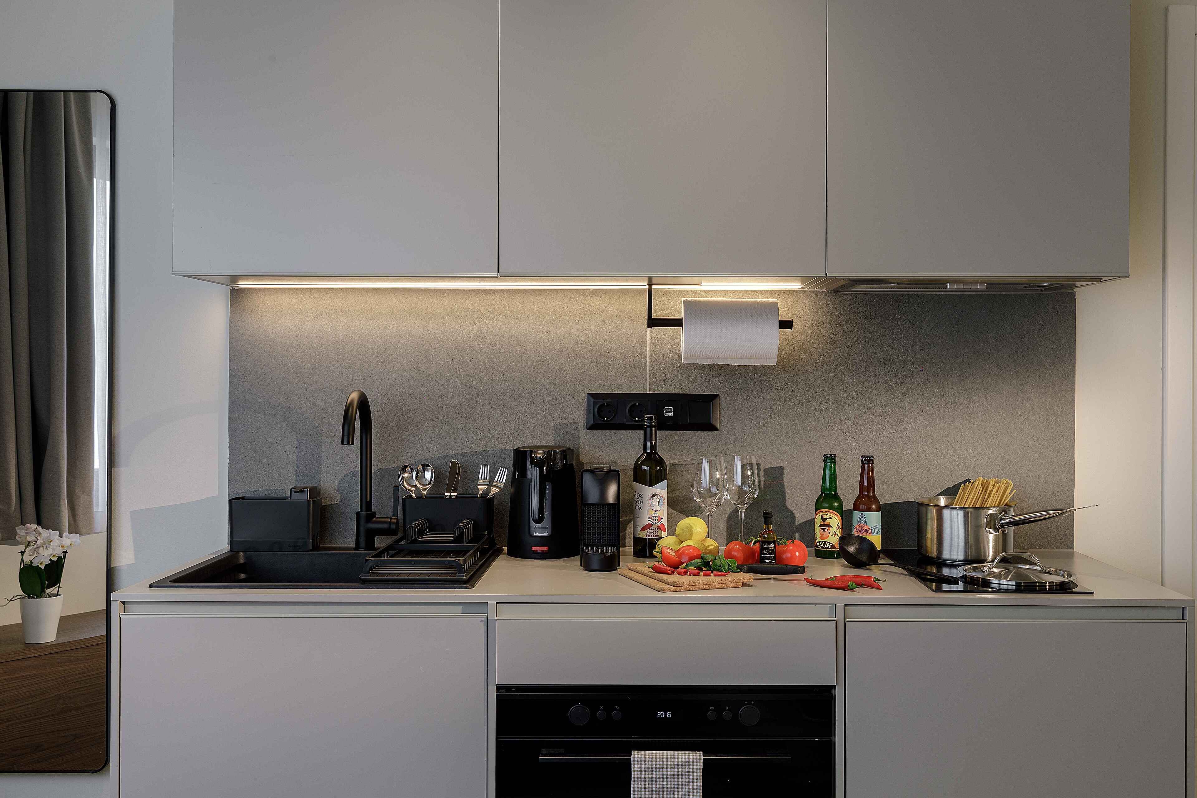 A modern kitchen with a built-in oven, a coffee maker, and a wine bottle.