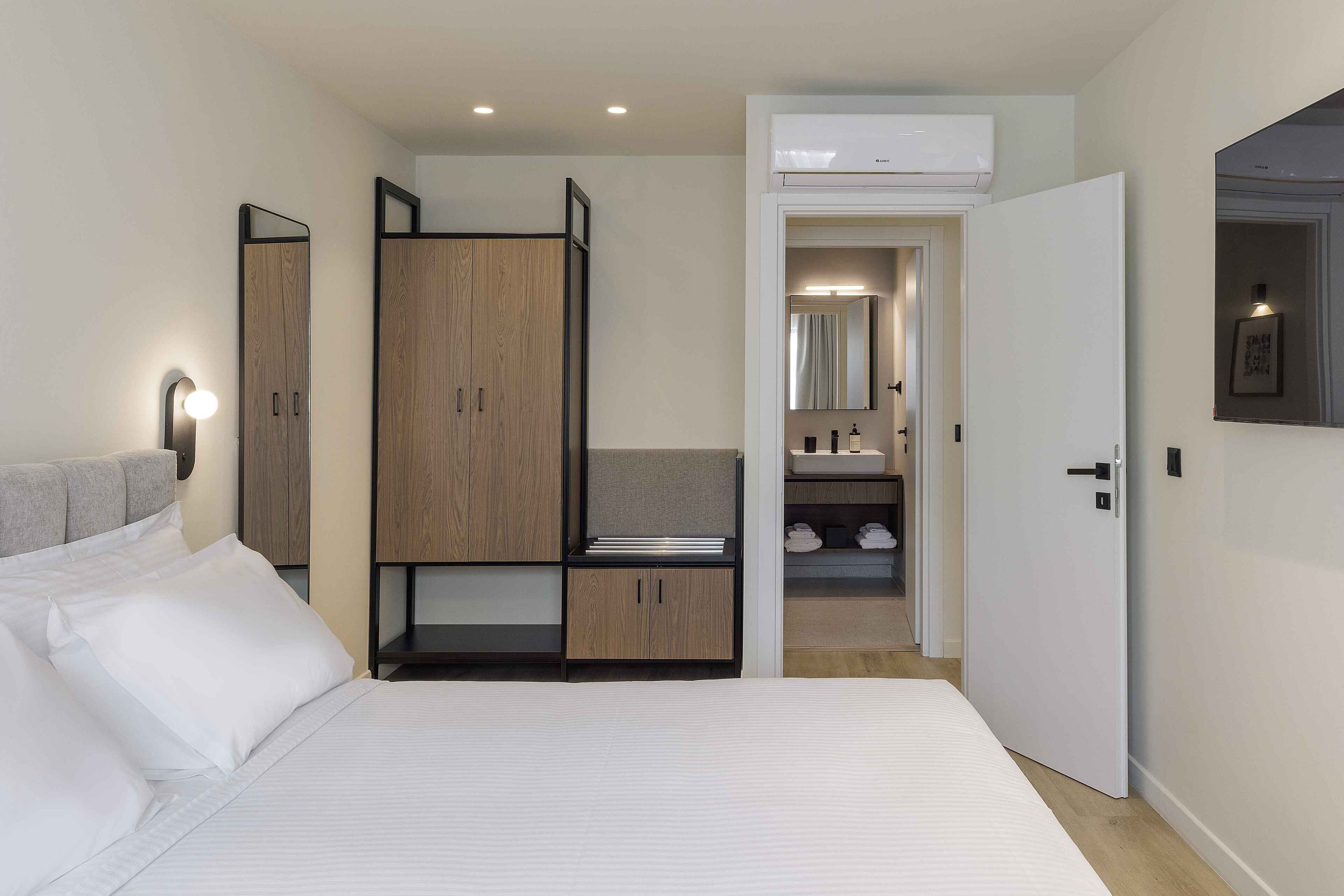 A bedroom with a bed, wardrobe, and a bathroom visible through an open door.