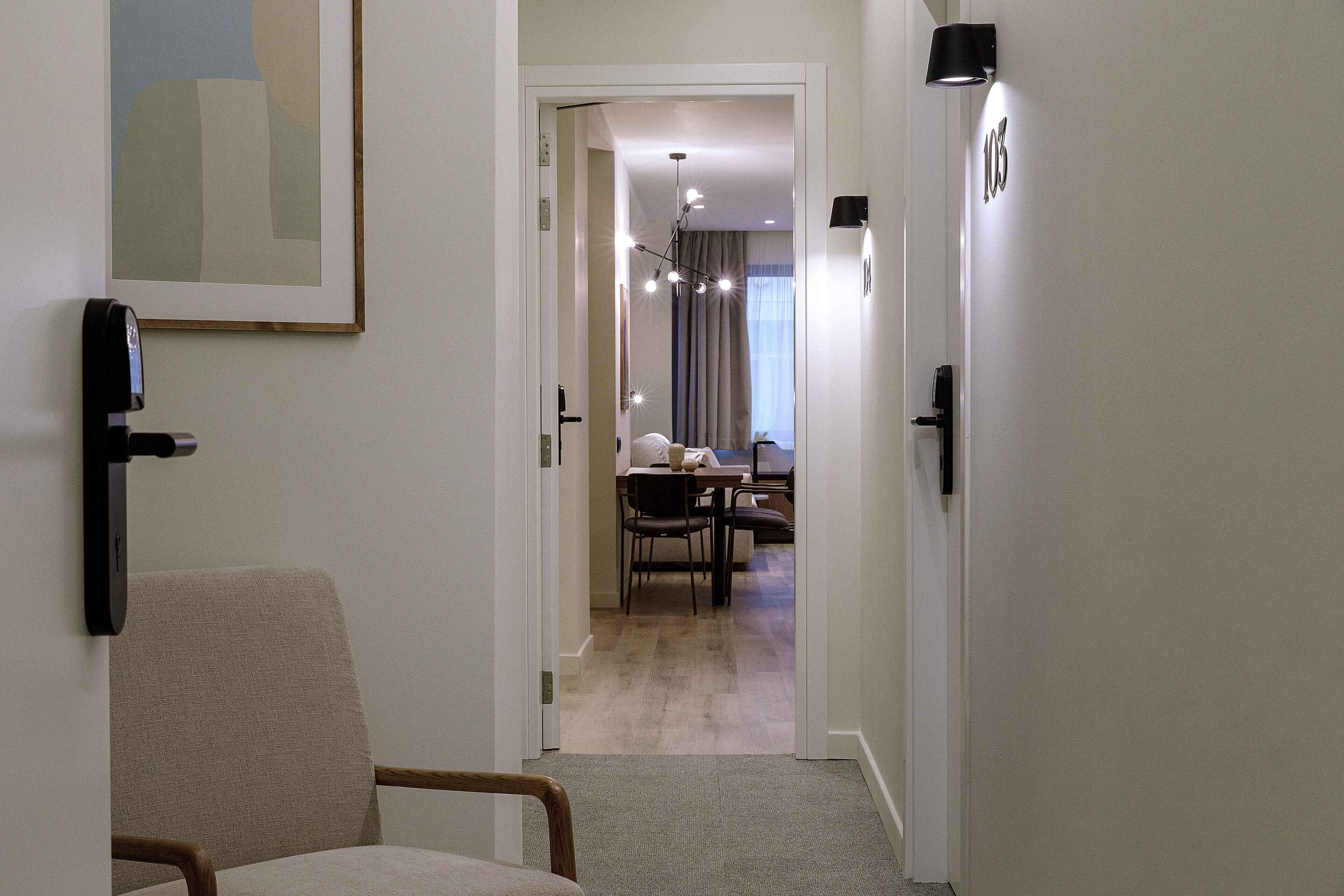 Un pasillo que conduce a un comedor con una mesa y sillas, un cuadro en la pared y una puerta con el número.