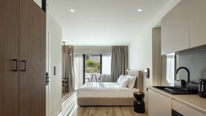 Habitació d'hotel moderna amb llit, petita cuina i vista a l'exterior.