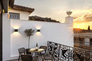 A terrace with a table set for dining, a potted plant, and a decorative railing. - master Plaka (Athens)