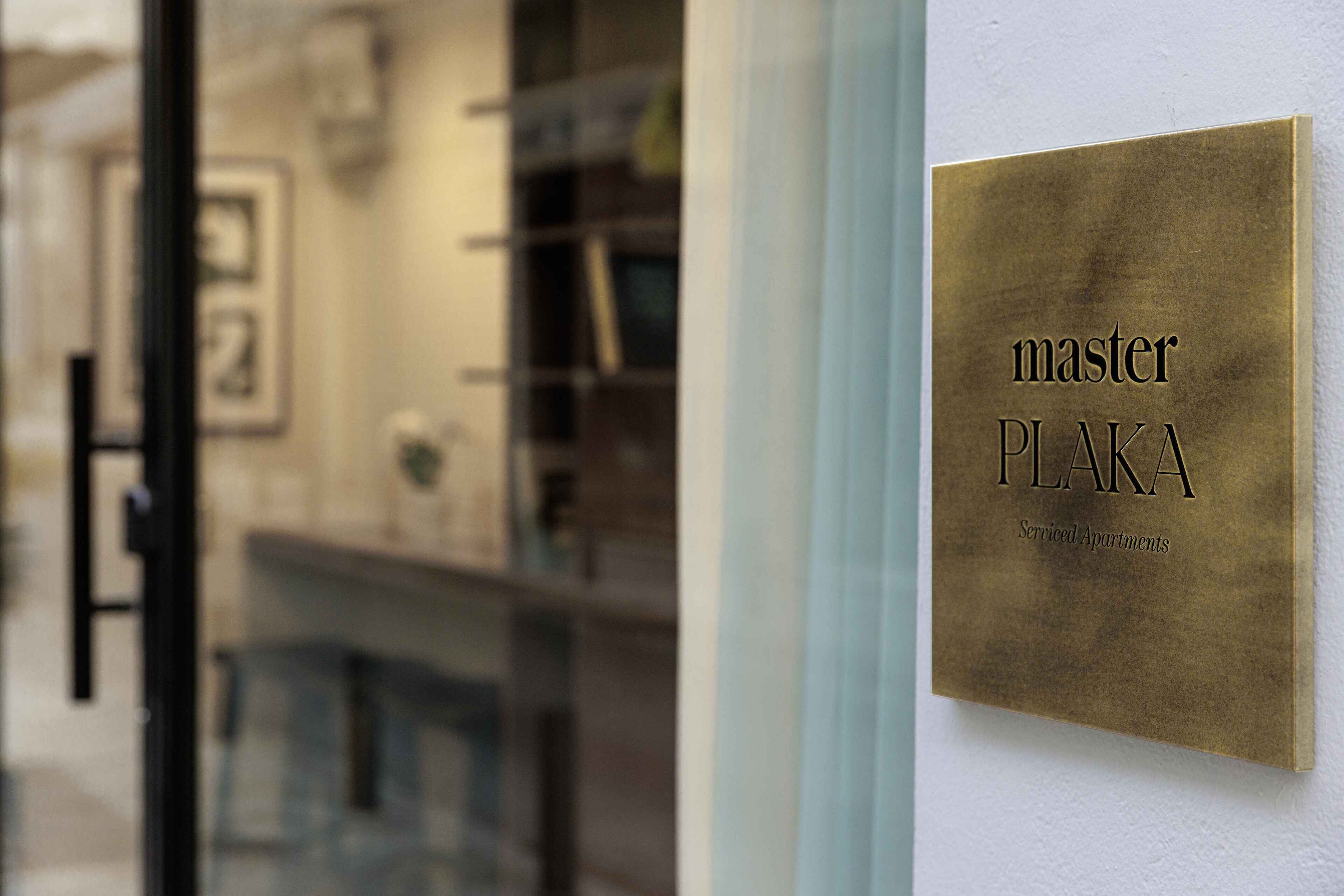 Et skilt med teksten 'master PLAKA Serviced Apartments' på en væg.