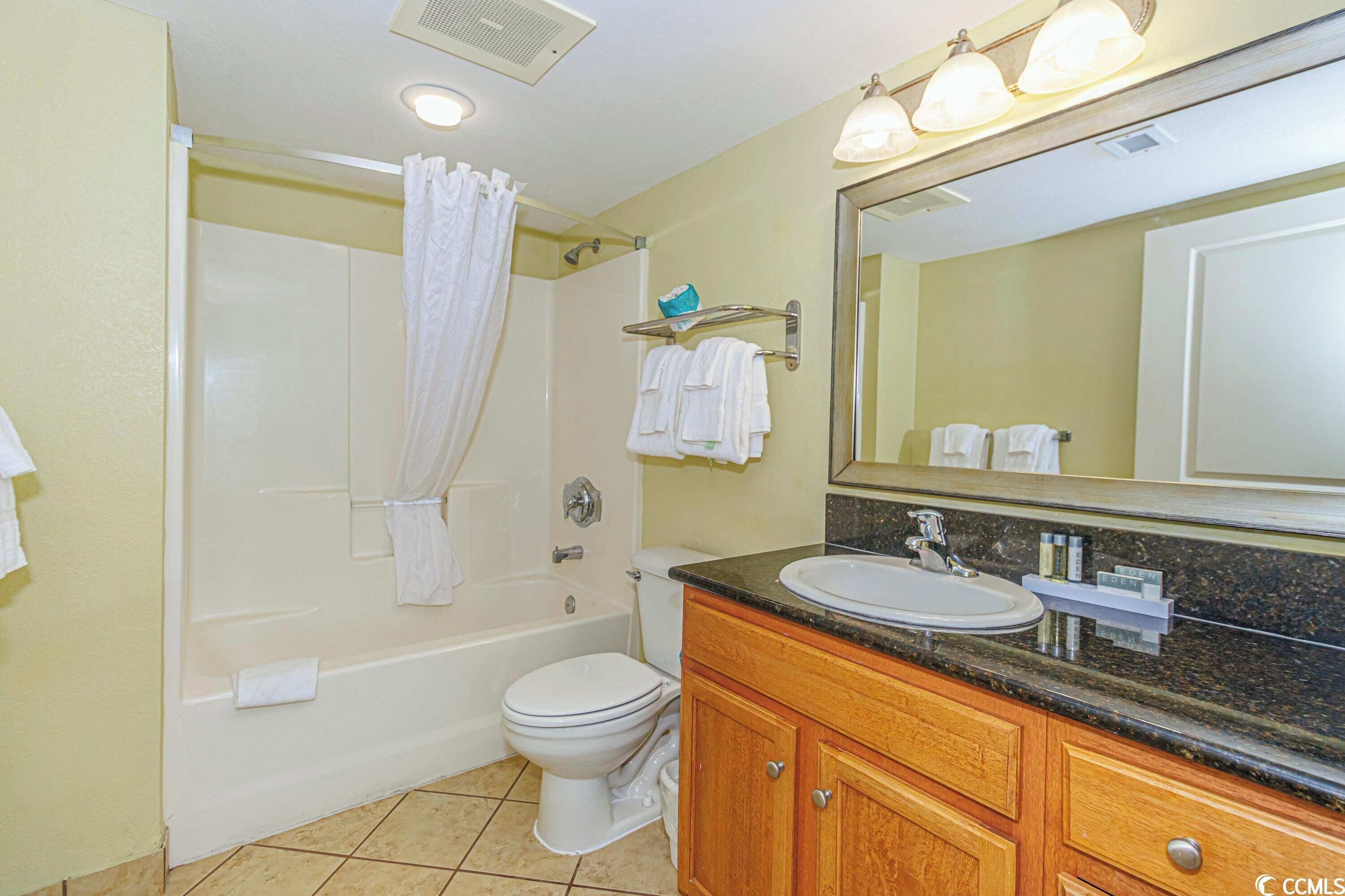 A bathroom with a bathtub, toilet, sink, and vanity.