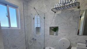 Et moderne badeværelse med bruseniche, toilet, vask og spejl.