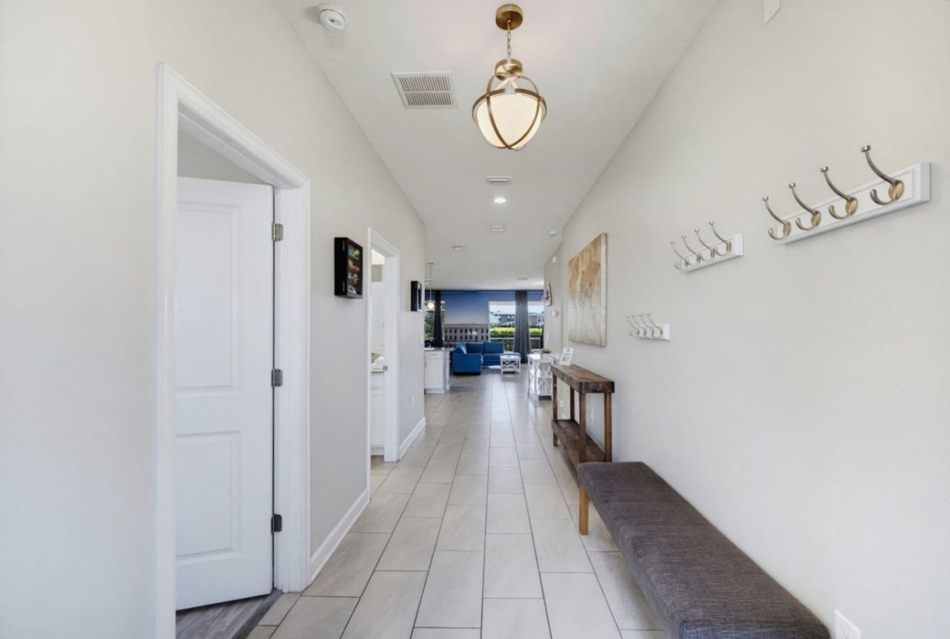 A hallway with a bench, a door, and a hanging light fixture.