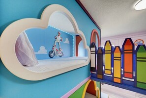 A children's play area with a cloud-shaped shelf, a motorcycle toy, and colorful fence decorations.