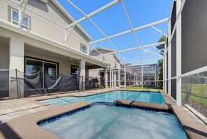 A swimming pool with a clear view of the sky, surrounded by a covered area with a metal frame structure.