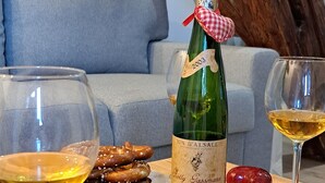 Una mesa de madera con una botella de vino, copas y platos de pretzels.