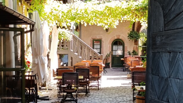 Un patio empedrado con mesas al aire libre y una escalera que lleva a un nivel superior.