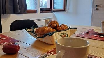 Une table à manger avec une tasse, une assiette et un panier de croissants.