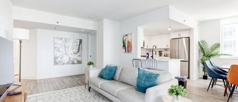 A modern living room with a sofa, coffee table, and a dining area with chairs.