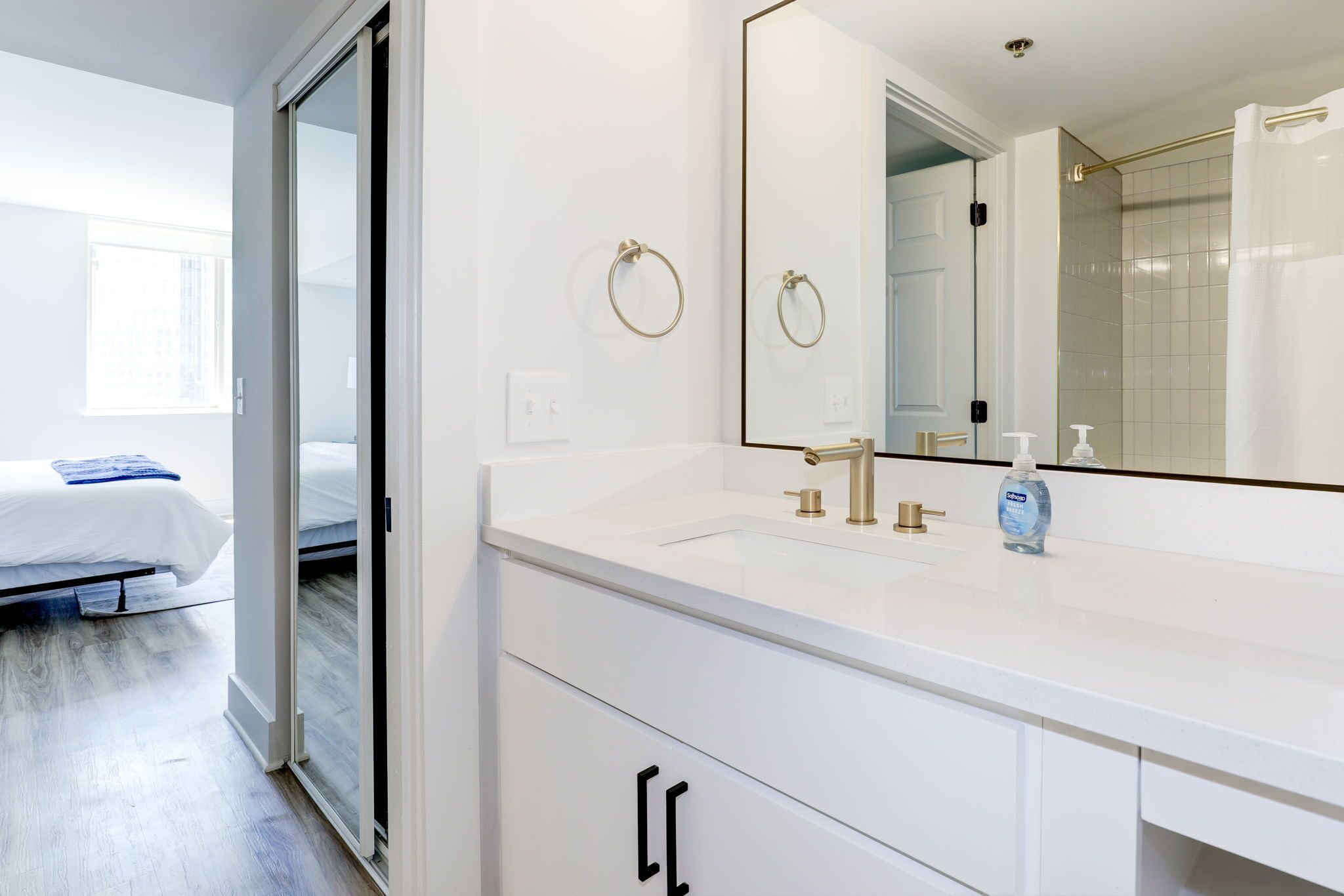 A modern bathroom with a white vanity, a large mirror, and a shower area.