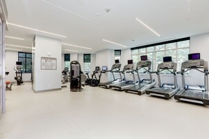 Et moderne fitnesscenter med løbebånd, crosstrainere og styrkeudstyr.