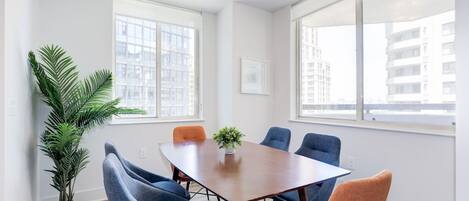 A conference room with a wooden table, six chairs, and a potted plant.