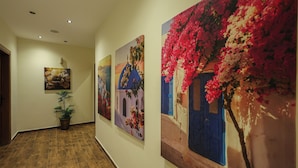 A hallway with wooden flooring, a potted plant, and three paintings on the wall. - Elite Boutique Hotel (New Cairo)