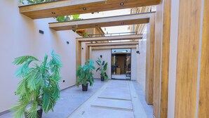 A covered walkway with potted plants, wooden beams, and a door leading to a room. - Elite Boutique Hotel (New Cairo)