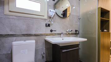 A bathroom with a toilet, sink, mirror, and a hairdryer on the wall.