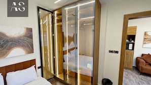 A hotel room with a bed, a wardrobe, a chair, and a wall-mounted artwork. - Elite Boutique Hotel (New Cairo)